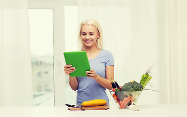 Image showing smiling young woman with tablet pc cooking at home