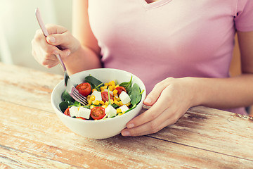 Image showing close up of young woman eating salad at home