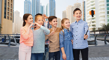 Image showing happy children with smartphone and selfie stick