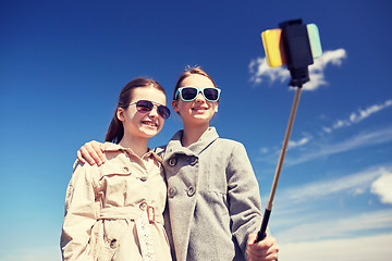 Image showing happy girls with smartphone selfie stick