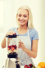 Image showing smiling woman with blender preparing shake at home