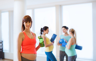 Image showing happy pregnant woman with water bottle in gym