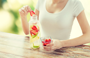 Image showing close up of woman with fruit water in glass bottle