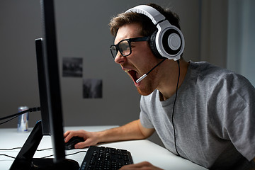 Image showing man in headset playing computer video game at home