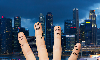 Image showing close up of fingers with smiley faces over city