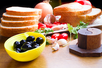 Image showing top-view of a wood table with olives tomatoes bread