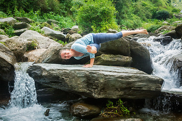 Image showing Young fit woman doing yoga oudoors at waterfall