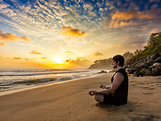 Image showing Young fit man do yoga meditation on tropical beach