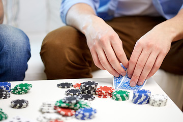 Image showing close up of male hand with playing cards and chips