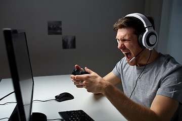 Image showing man in headset playing computer video game at home