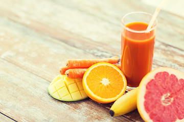 Image showing close up of fresh juice glass and fruits on table