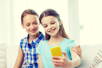 Image showing happy girls with smartphone taking selfie at home