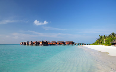 Image showing bungalow huts in sea water on exotic resort beach