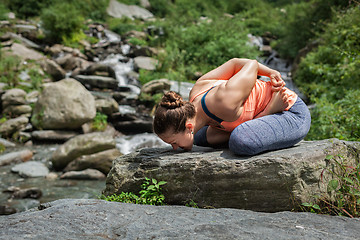 Image showing Young woman does yoga oudoors at waterfall