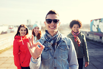 Image showing happy teenage friends showing ok sign on street