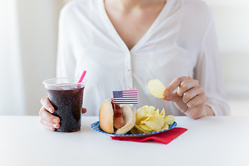 Image showing close up of woman eating chips, hot dog and cola