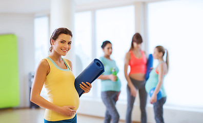 Image showing happy pregnant woman with mat in gym