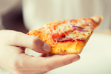 Image showing close up of hand holding pizza slice