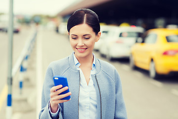 Image showing smiling woman with smartphone over taxi in city