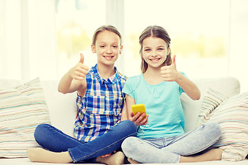 Image showing happy girls with smartphone sitting on sofa