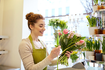 Image showing smiling florist woman making bunch at flower shop