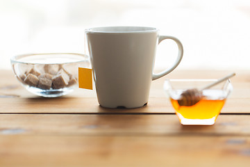 Image showing close up tea cup with honey and sugar on table