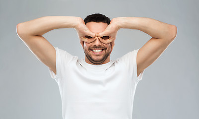 Image showing man making finger glasses over gray background