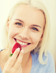 Image showing happy woman eating strawberry at home