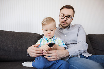 Image showing father and son with remote watching tv at home