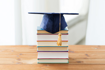 Image showing close up of books and mortarboard on wooden table