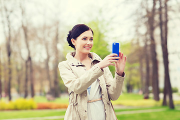 Image showing smiling woman taking picture with smartphone