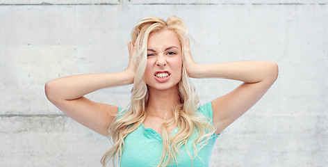 Image showing young woman holding to her head and screaming