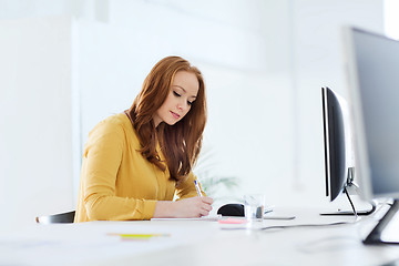 Image showing creative female office worker writing to notebook