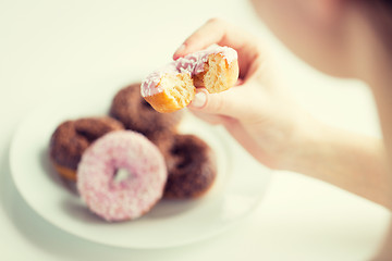 Image showing close up of hand holding bitten glazed donut