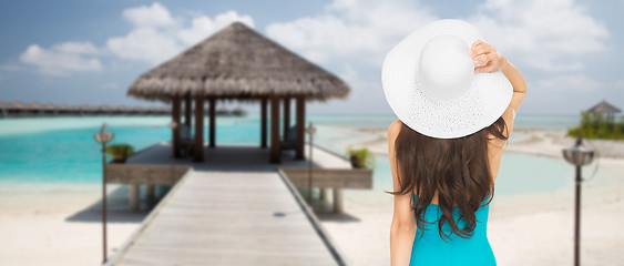 Image showing woman in swimsuit and sun hat from back on beach