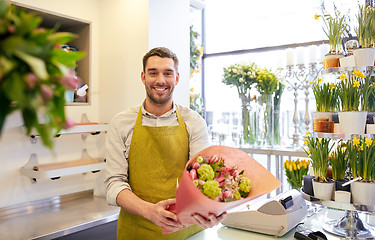 Image showing smiling florist man making bunch at flower shop