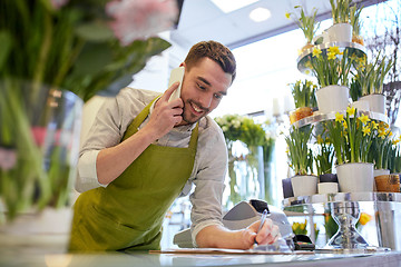 Image showing man with smartphone making notes at flower shop