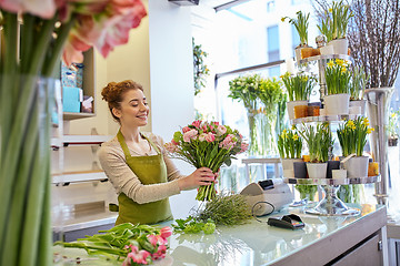 Image showing smiling florist woman making bunch at flower shop