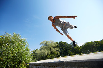 Image showing sporty young man jumping in summer park