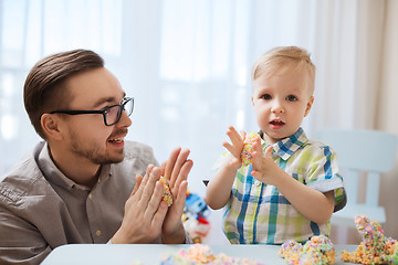 Image showing father and son playing with ball clay at home