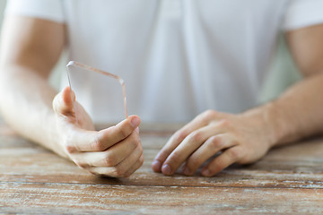 Image showing close up of male hand with transparent smartphone
