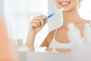 Image showing woman with toothbrush cleaning teeth at bathroom