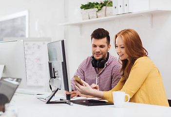 Image showing smiling creative team with smartphones at office