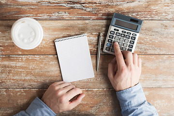 Image showing close up of hands with calculator and notebook