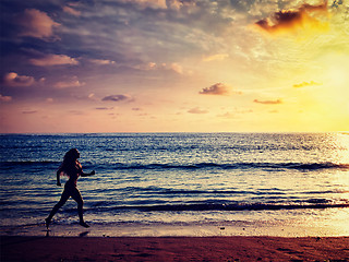 Image showing Beautiful athletic woman running along sea on the beach