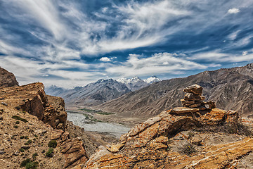 Image showing View of valley in Himalayas with stone cairn on cliff