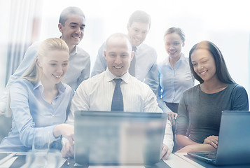 Image showing smiling business people with laptop in office