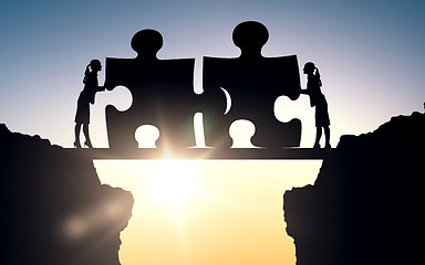 Image showing silhouette of two business women connecting puzzle