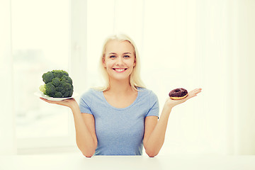 Image showing smiling woman with broccoli and donut at home