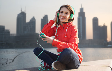 Image showing happy young woman with smartphone and headphones